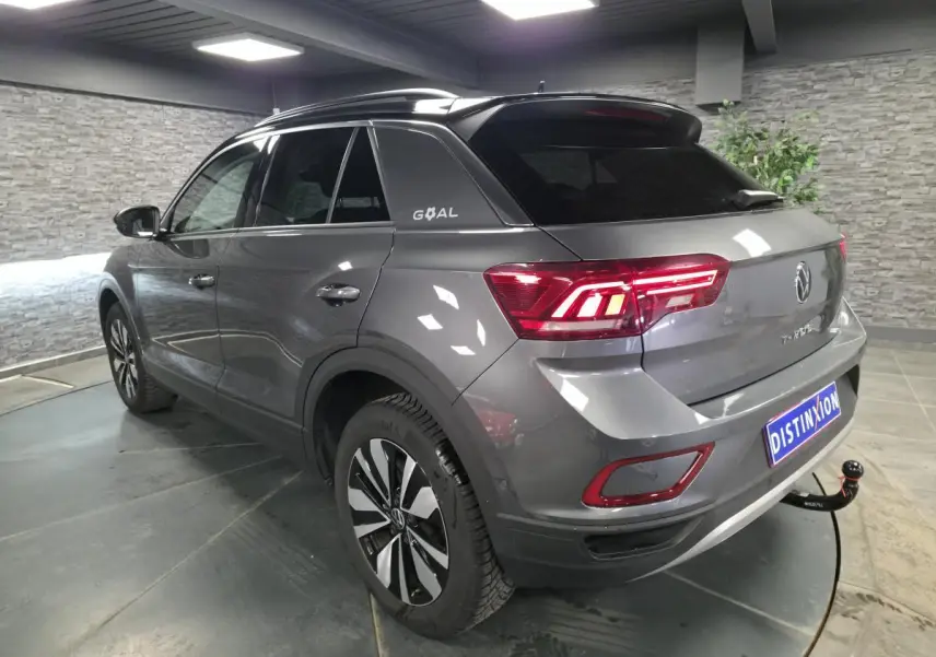Volkswagen T-Roc gris en 3/4 arrière droit, toit noir avec logo GOAL et attelage démontable visible.