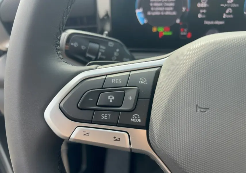 Gros plan sur le volant cuir multifonctions gris d’un Volkswagen T-Roc 2026, avec commandes de régulateur de vitesse.