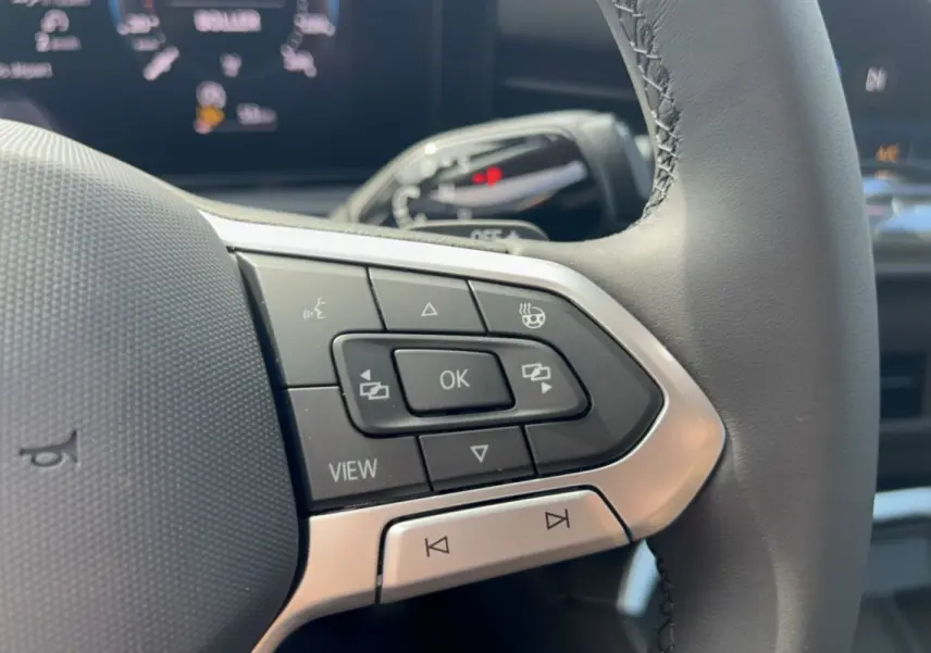 Gros plan sur les commandes multifonctions à gauche du volant cuir du Volkswagen T-Roc gris loup 2026.