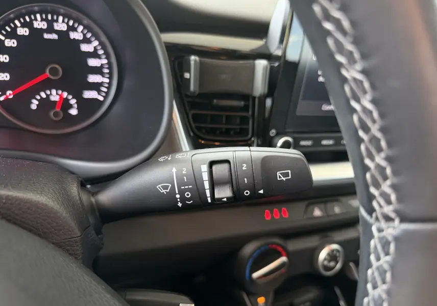 Gros plan sur la commande d’essuie-glace à gauche du volant dans l’habitacle noir du Kia Stonic blanc 2022.
