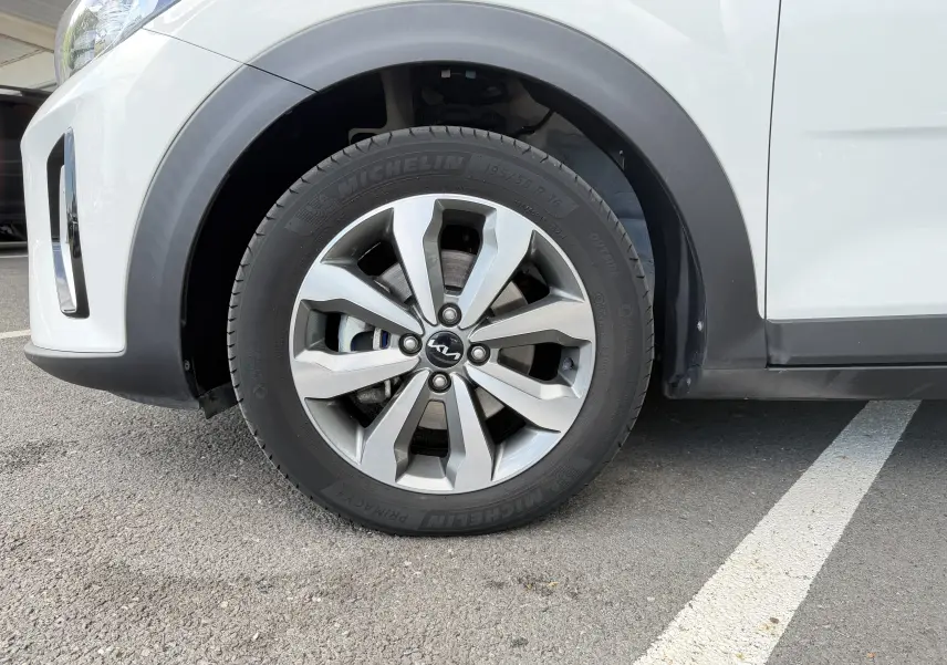 Gros plan sur la roue avant gauche d’un KIA Stonic blanc avec jante alliage et pneu Michelin.