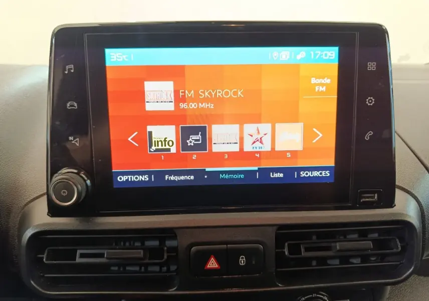 Écran tactile central du tableau de bord du Citroën Berlingo blanc, affichant une radio FM.