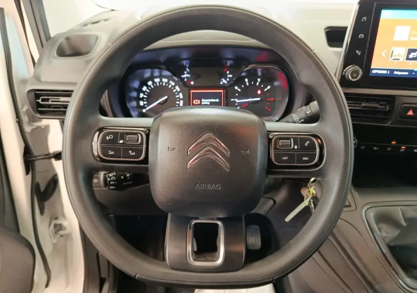 Vue centrée sur le volant multifonctions noir du Citroën Berlingo blanc, avec tableau de bord et écran tactile visibles.