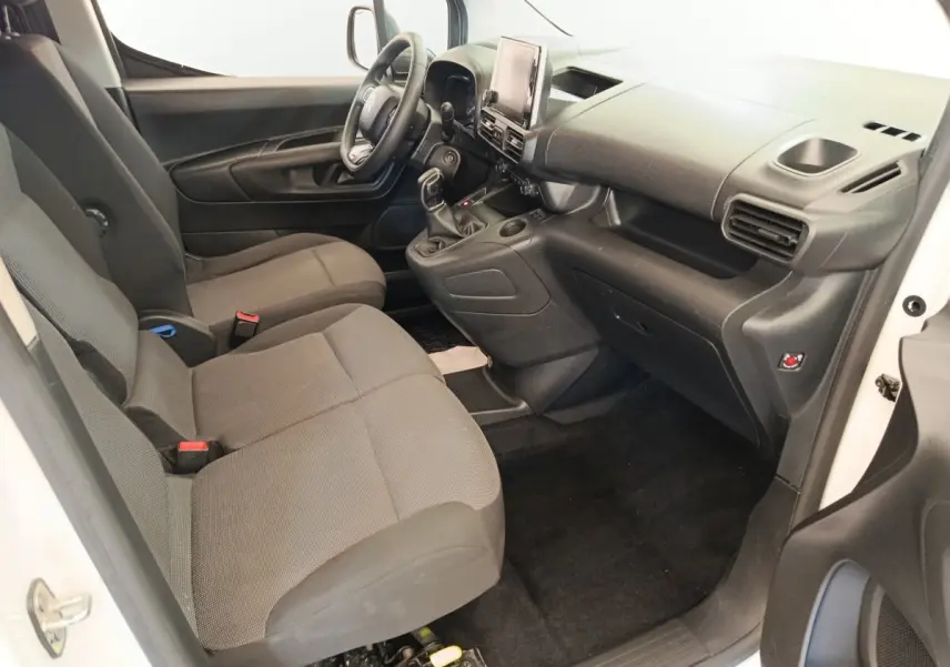 Vue intérieure côté conducteur du Citroën Berlingo blanc 2020, montrant sièges tissu gris et tableau de bord noir.