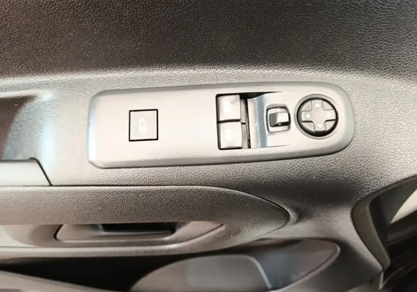 Vue rapprochée des commandes de lève-vitres et réglage des rétroviseurs sur la porte côté conducteur d’un Citroën Berlingo blanc.
