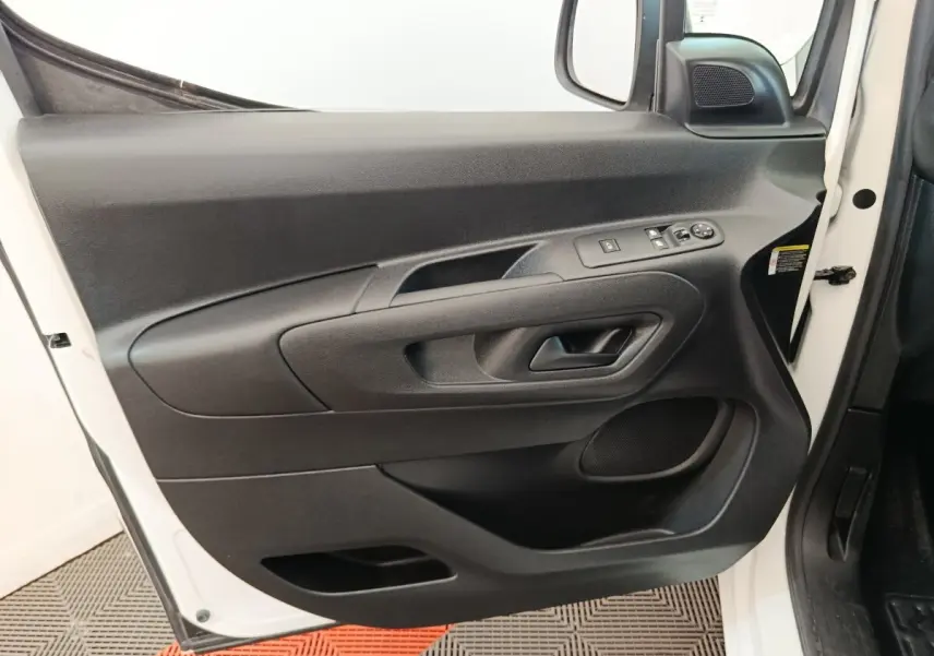 Vue rapprochée de la porte avant gauche noire du Citroën Berlingo blanc, avec commandes électriques des vitres et rétroviseur.