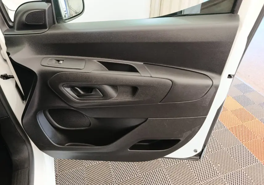 Vue rapprochée de la porte avant gauche noire du Citroën Berlingo blanc, montrant la poignée et la commande de vitre.
