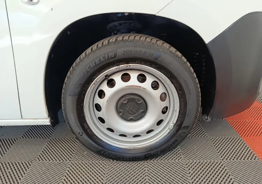 Gros plan sur la roue avant droite blanche en jante acier du Citroën Berlingo blanc, avec logo central visible.