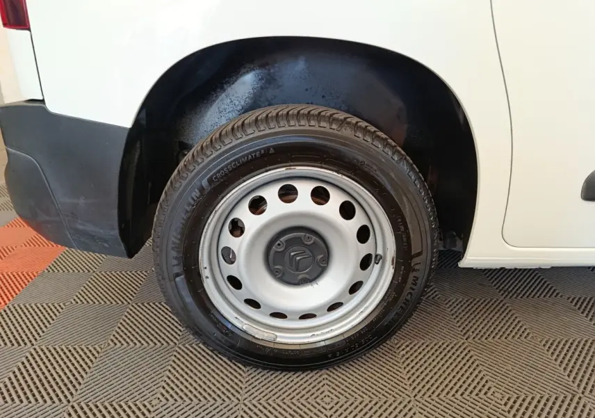 Gros plan sur la roue arrière droite en jante acier du Citroën Berlingo blanc, avec partie basse de la carrosserie visible.