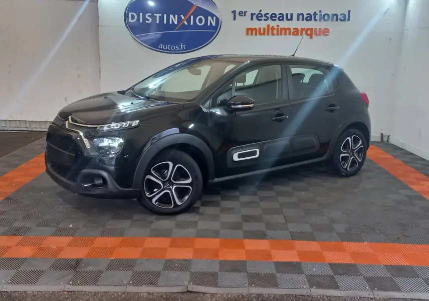 Citroën C3 noire vue de profil droit en intérieur, avec protections latérales blanches et jantes distinctives.
