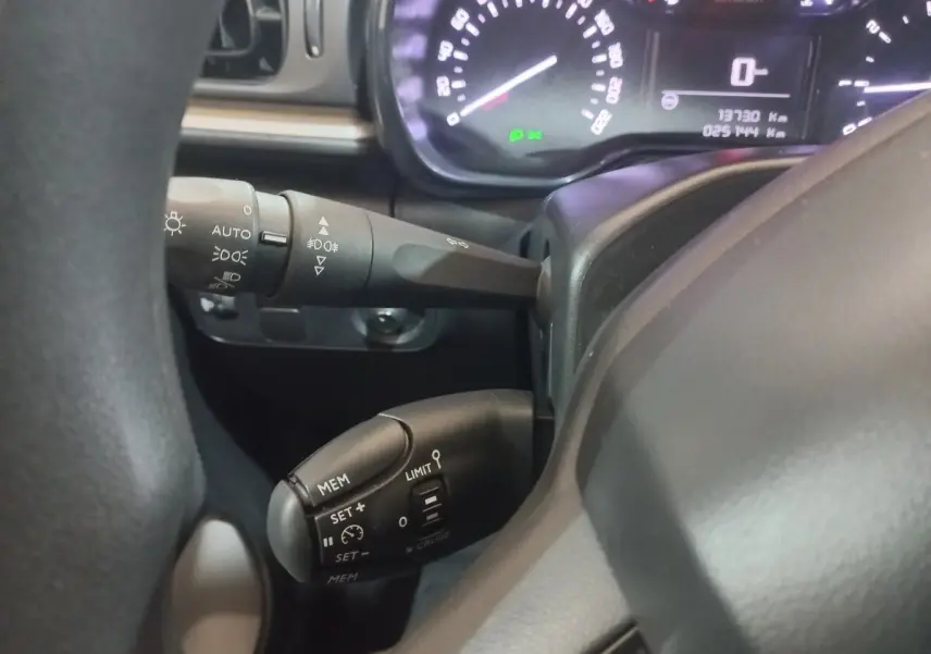 Gros plan sur le volant noir et les commandes de régulateur de vitesse de la Citroën C3 2024, tableau de bord en arrière-plan.
