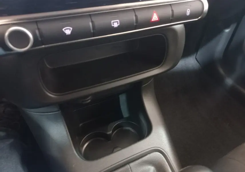 Vue rapprochée de la console centrale noire de la Citroën C3 2024, avec porte-gobelets et boutons de commande.