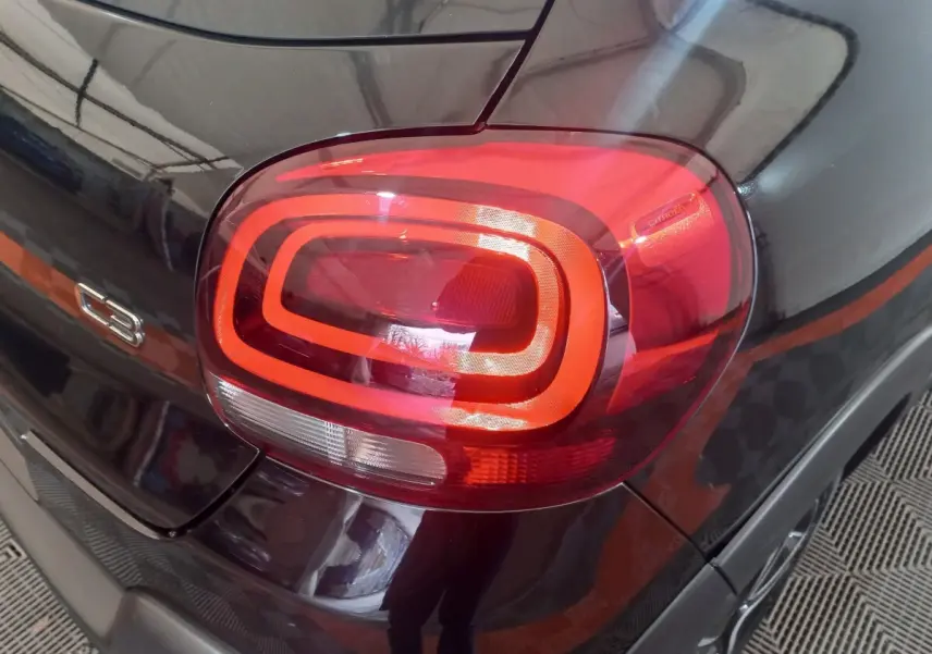 Gros plan sur le feu arrière droit rouge et noir brillant d'une Citroën C3 2024, avec logo et badge C3 visibles.
