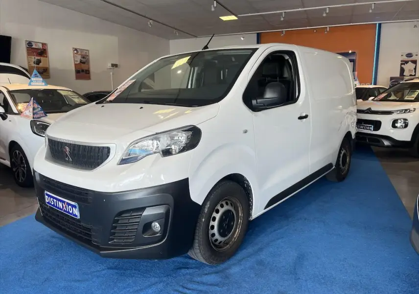 Vue 3/4 avant d'un Peugeot Expert Fourgon blanc avec pare-chocs noir dans un showroom.