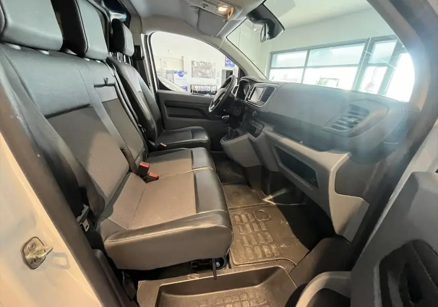 Vue intérieure côté conducteur du Peugeot Expert Fourgon blanc 2019, sièges avant modulables en tissu gris et noir.