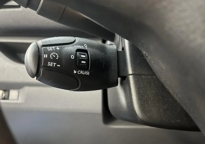 Gros plan sur la commande de régulateur de vitesse noire du Peugeot Expert Fourgon blanc, côté conducteur.