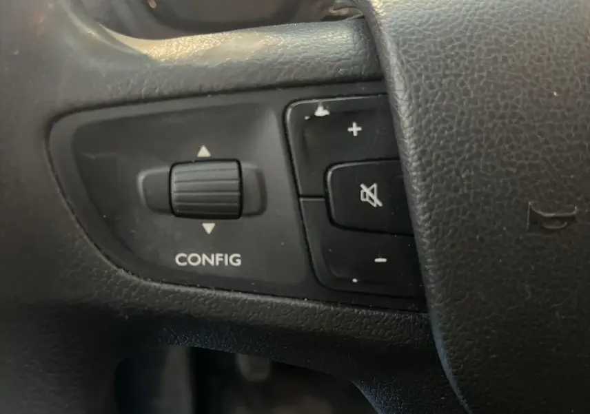 Gros plan sur les commandes noires du volant du Peugeot Expert Fourgon blanc, avec bouton config et réglage volume.