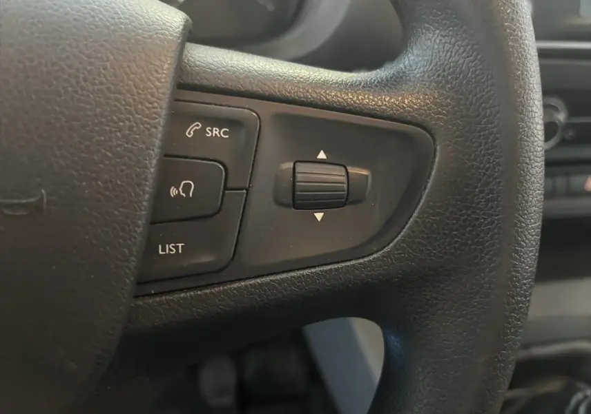Gros plan sur les commandes audio au volant noir du Peugeot Expert Fourgon blanc, version 2019, côté gauche.