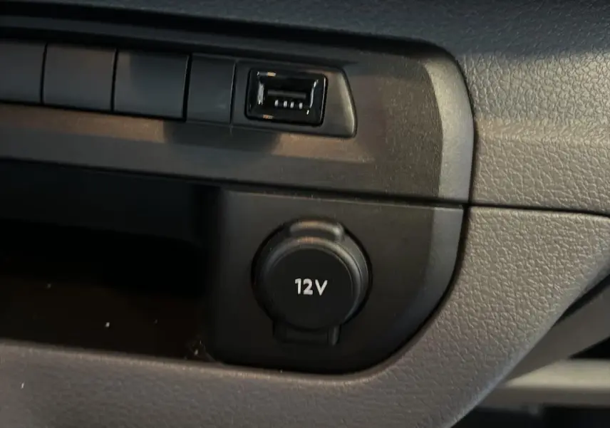 Gros plan sur la prise 12V et port USB du tableau de bord noir du Peugeot Expert Fourgon blanc de 2019.