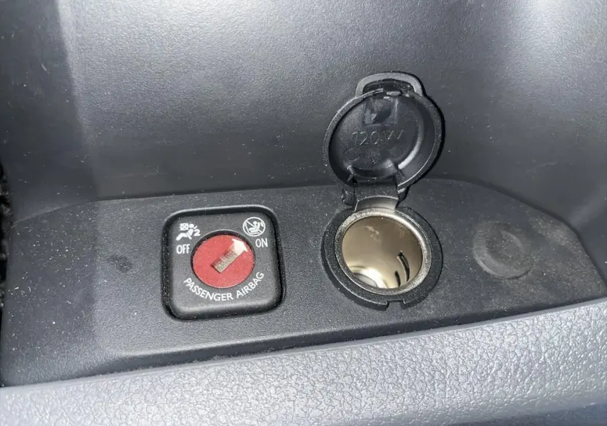 Gros plan sur l'interrupteur d'airbag passager et prise 12V dans l'habitacle du Peugeot Expert Fourgon blanc.