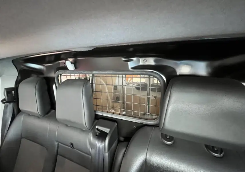Vue intérieure arrière du Peugeot Expert Fourgon blanc de 2019, montrant les sièges noirs et la grille de séparation du coffre.