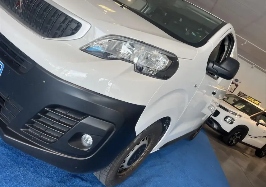 Vue 3/4 avant droit d'un Peugeot Expert Fourgon blanc avec pare-chocs noir et rétroviseur noir en showroom.