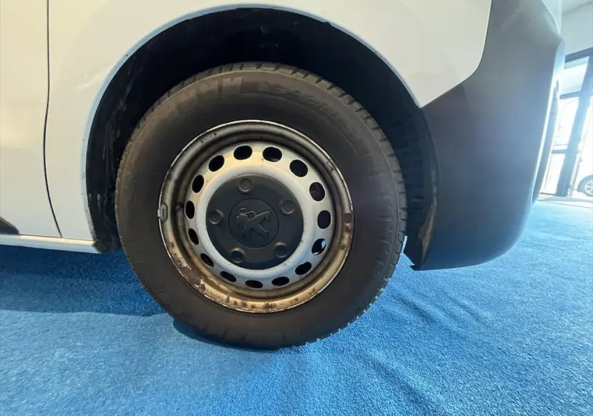 Gros plan sur la roue avant droite du Peugeot Expert Fourgon blanc, avec jante acier et logo Peugeot au centre.