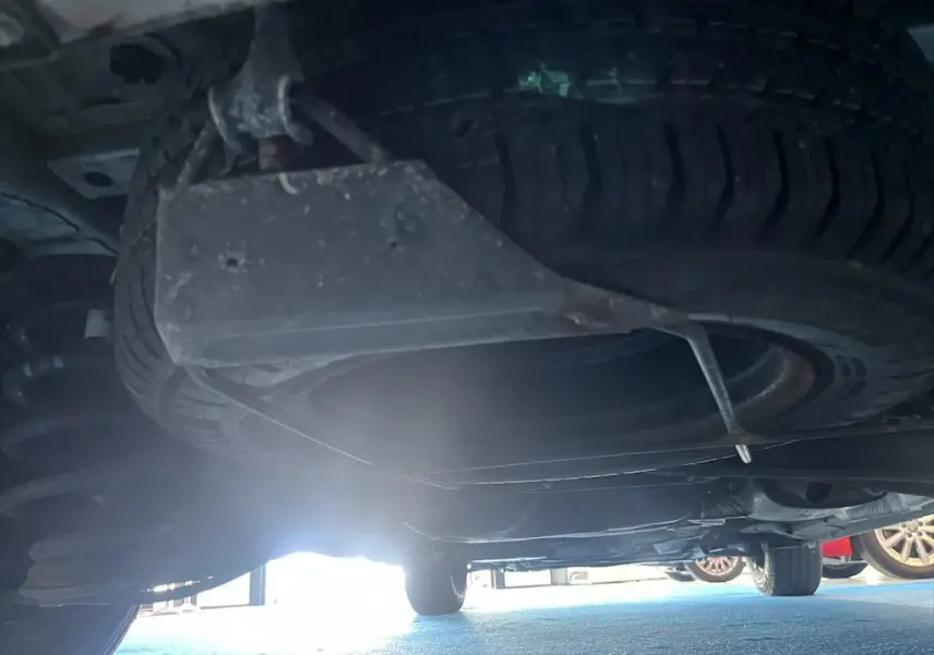 Vue sous le Peugeot Expert Fourgon blanc montrant la roue de secours suspendue sous le châssis arrière.