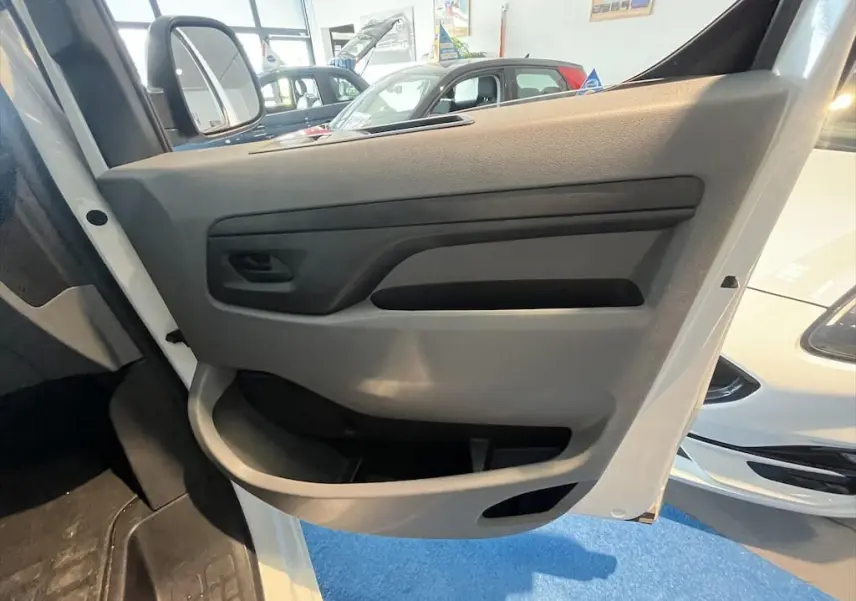 Vue rapprochée de la porte avant gauche blanche du Peugeot Expert Fourgon 2019, intérieur gris avec poignée noire.
