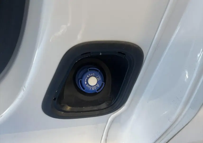 Gros plan sur le bouchon bleu AdBlue du Peugeot Expert Fourgon blanc, situé dans l'encadrement de porte.