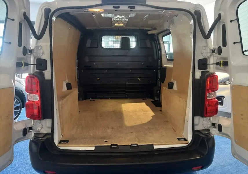 Vue arrière intérieure du Peugeot Expert Fourgon blanc 2019, montrant l'espace de chargement avec parois en bois et cloison métallique.