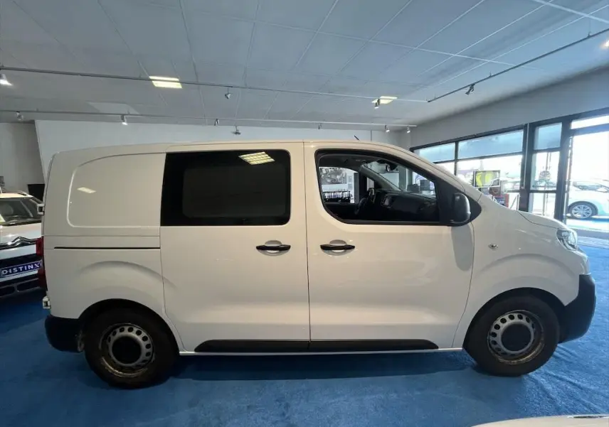 Profil côté gauche d'un Peugeot Expert Fourgon blanc 2019 en intérieur, avec fenêtres teintées et jantes acier.