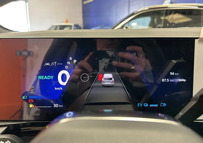 Tableau de bord numérique du Renault Austral blanc nacré, affichant la vitesse à 0 km/h et porte arrière gauche ouverte.