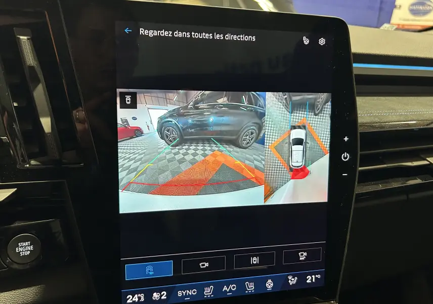 Écran tactile du Renault Austral Ph.2 blanc nacré montrant la caméra 360° avec vue arrière et vue aérienne du véhicule.