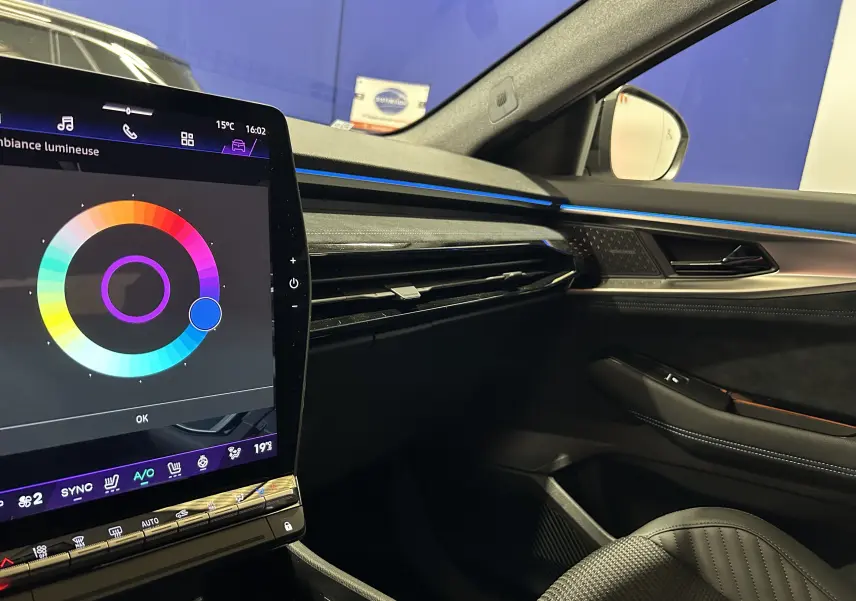 Vue intérieure côté passager du Renault Austral blanc nacré satin, avec écran tactile et éclairage d'ambiance bleu.