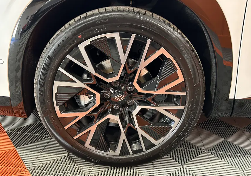 Gros plan sur la jante avant droite noire et argentée du Renault Austral blanc nacré satin, avec pneu Michelin visible.