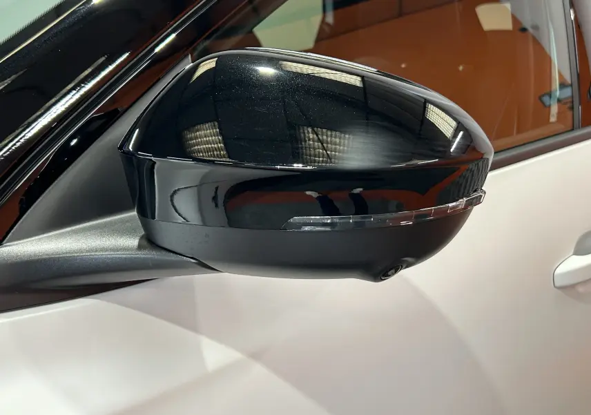 Rétroviseur noir brillant côté gauche du Renault Austral blanc nacré satin, avec caméra intégrée sous le miroir.