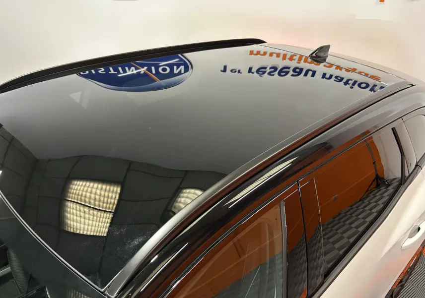 Toit panoramique en verre noir sur Renault Austral blanc nacré, vue en plongée côté droit avant du véhicule.