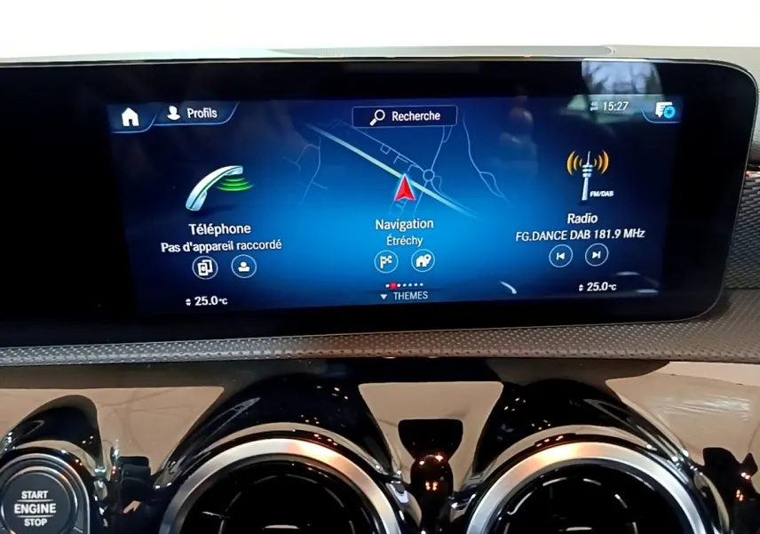 Vue rapprochée de l’écran tactile central et des aérateurs ronds chromés du tableau de bord de la Mercedes CLA 180 d blanche.