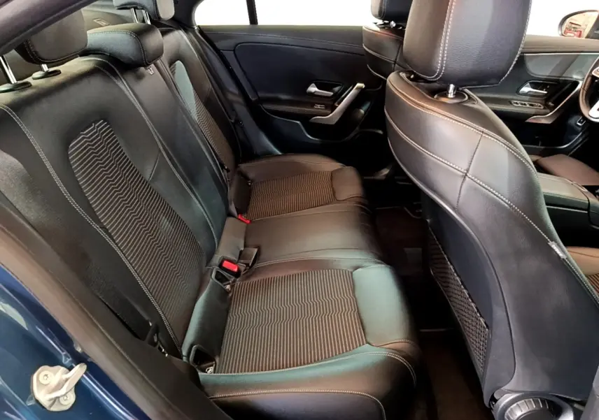 Vue intérieure arrière côté gauche sur les sièges noirs en cuir et tissu de la Mercedes CLA 180 d Business Line blanche.