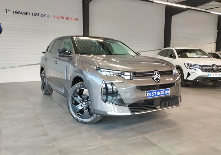 Vue 3/4 avant d'un Citroën C5 Aircross gris platine avec jantes alliage noires dans un showroom.