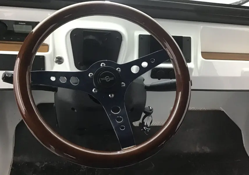 Vue rapprochée du volant bois brun du MLT E-STORY ICONE 2024 blanc/bleu avec tableau de bord minimaliste blanc.