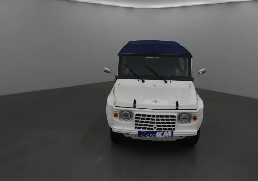 Vue avant d'une MLT E-STORY ICONE blanche avec toit bleu, calandre ajourée et phares ronds.