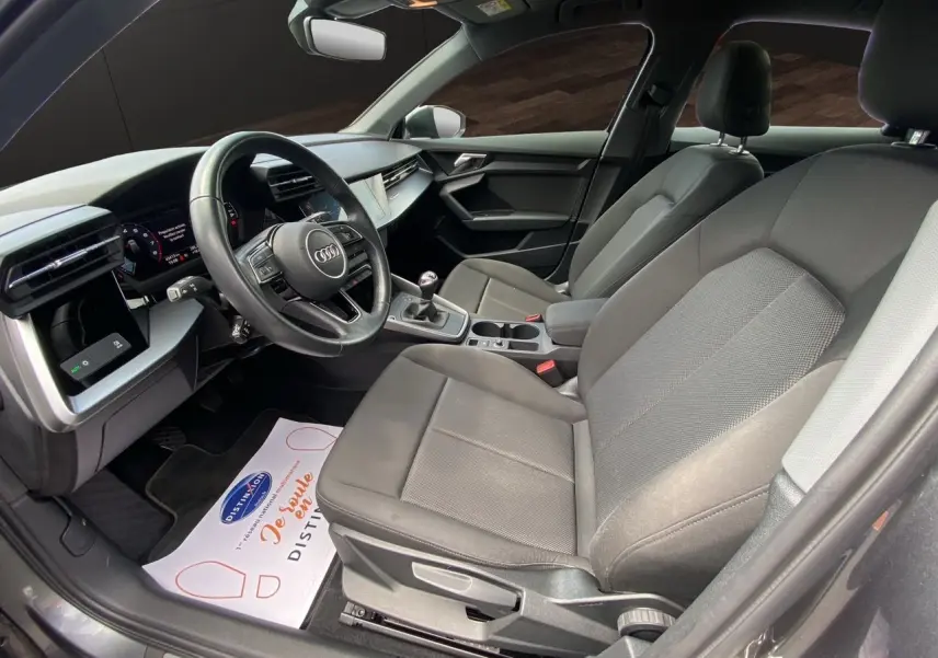 Intérieur noir de l'Audi A3 Sportback 30 TFSI 110 S-Line 2021, vue côté conducteur avec tableau de bord et sièges en tissu.