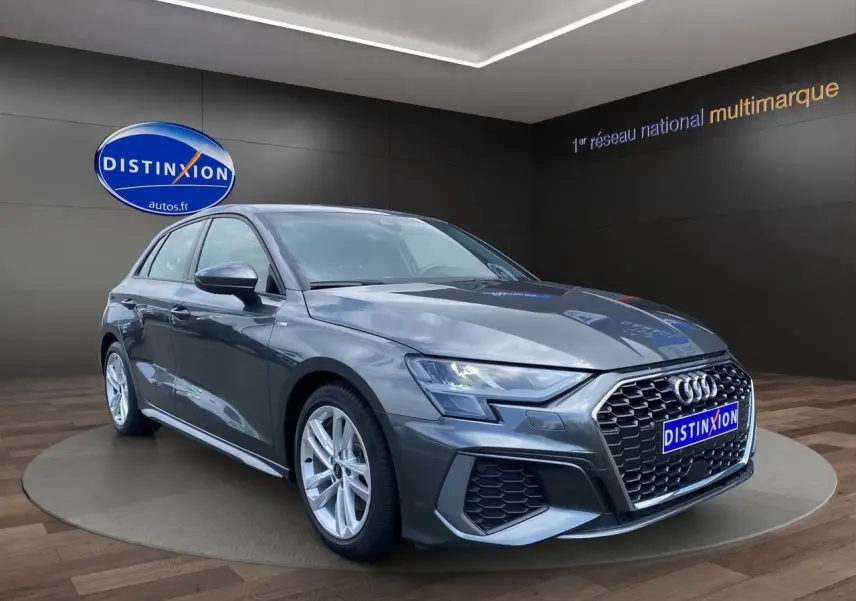 Audi A3 Sportback gris Daytona vue 3/4 avant droit, avec calandre hexagonale et jantes alliage argentées.