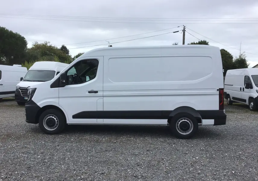 Vue de profil côté gauche d'un utilitaire Renault Master blanc L2H2 avec protections noires sur un parking extérieur.