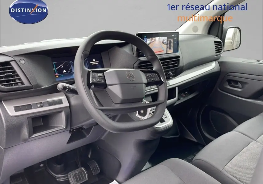 Vue intérieure côté conducteur du Citroën Jumpy gris avec tableau de bord moderne et écran de caméra de recul.