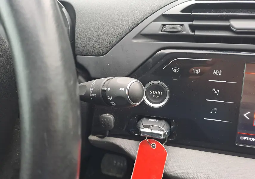 Gros plan sur le tableau de bord noir de la Citroën C4 Spacetourer avec bouton start/stop et clé à étiquette rouge.