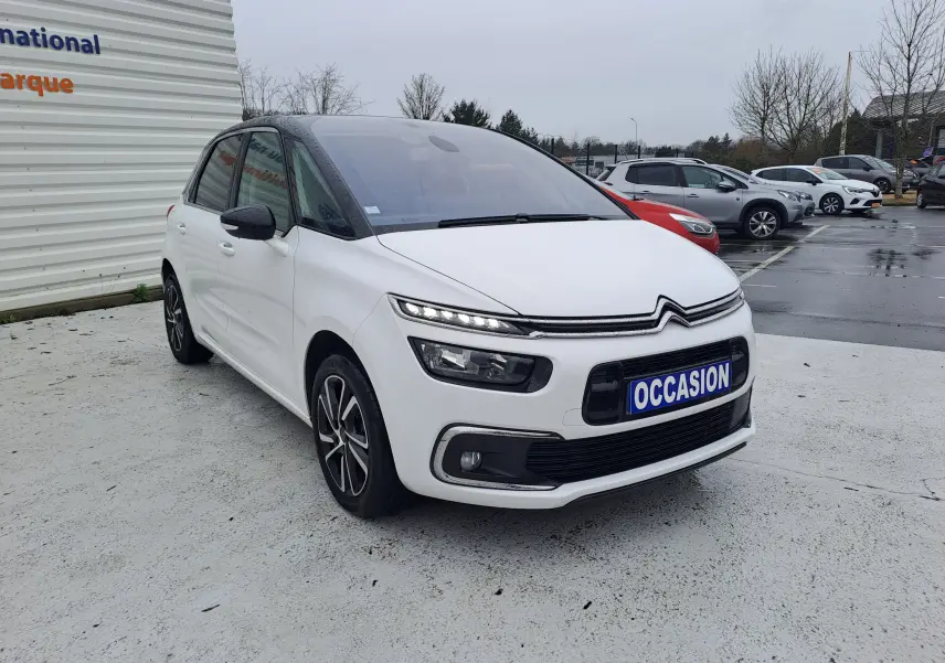 Citroën C4 Spacetourer blanc vue 3/4 avant droit avec toit noir et jantes bi-ton sur parking humide.