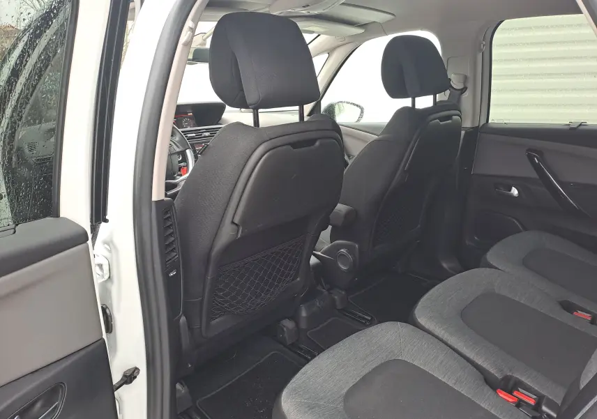 Vue intérieure arrière droite du Citroën C4 Spacetourer blanc 2018, montrant les sièges tissu gris et les dossiers avant avec filets de rangement.